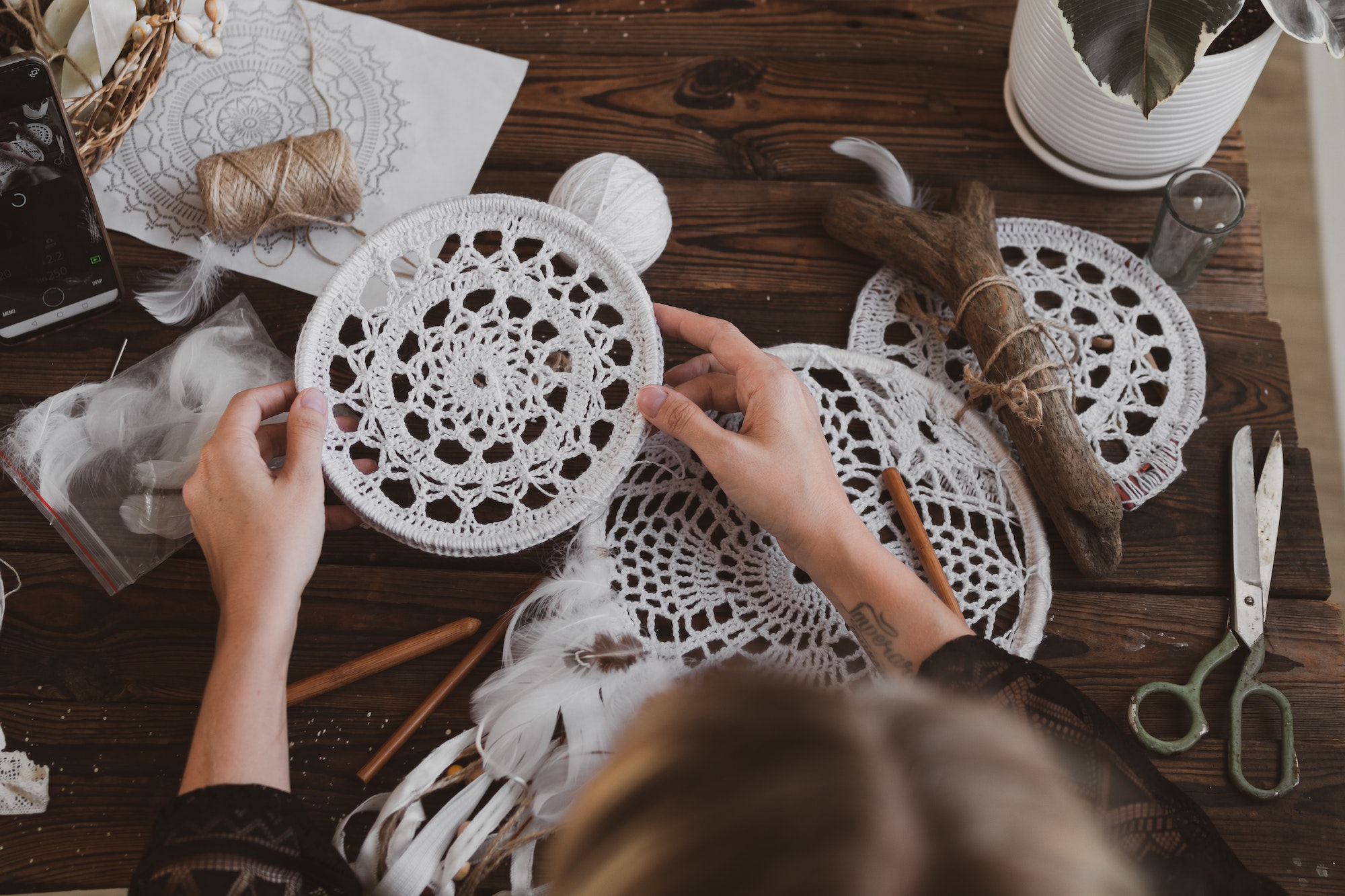 young woman knitting dreamcatchers at acozy work table. hobby, craft concept